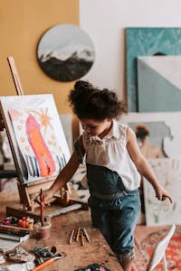 Child artist painting at an indoor studio easel with vibrant creativity.